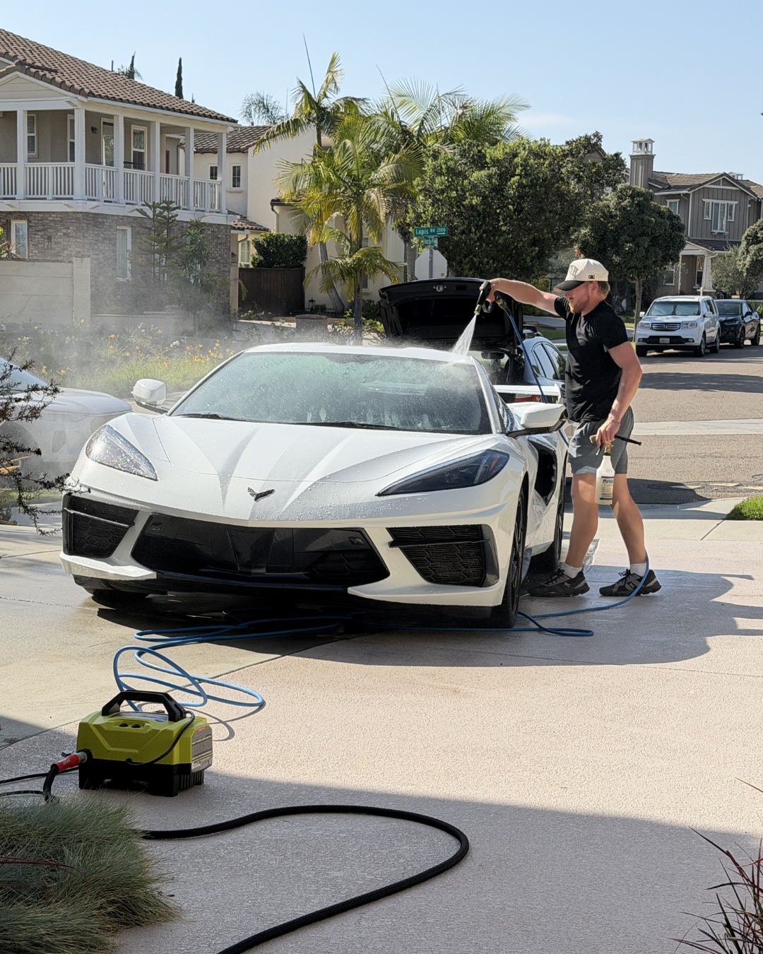 Jacob Crain, owner of Mobile Detailing Glendale, pressure washing a Corvette C8 in a Glendale, AZ driveway